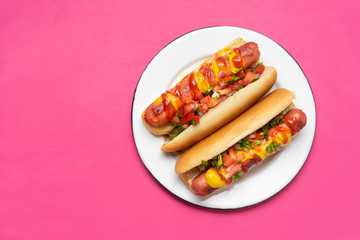 Hot dog with pico de gallo salad on pink background