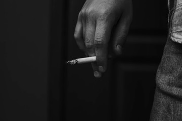the man is holding a cigarette in his hand. black and white photo