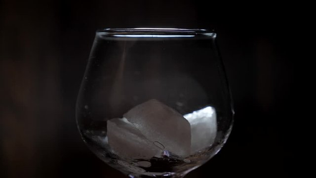 glass with whiskey and ice cubes