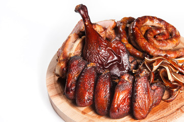 Appetizing set of smoked meat: spiral fried sausage, chicken leg, buffalo chicken wings, sliced smoked meat. On a wooden tray. On a white background in isolation.