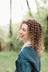 Portrait of laughing and smiling girl with curly hair on green and wooden background