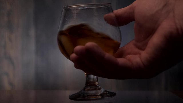 Hand shaking a glass of whiskey