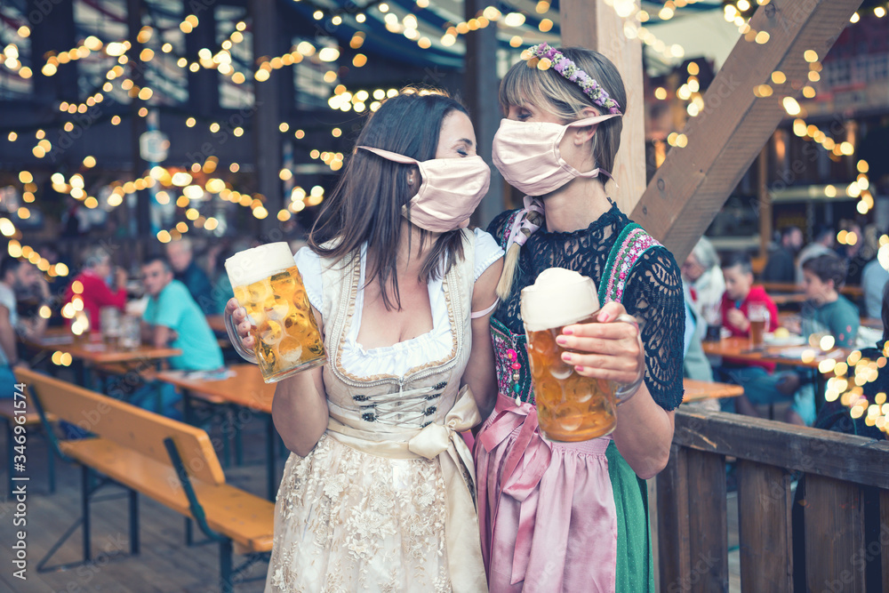 Wall mural two women in dirndl, traditional fashion with mask on okoberfest 