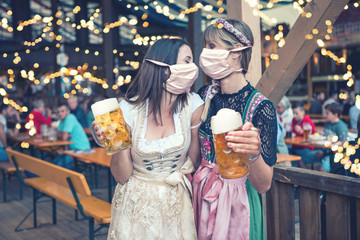 two women in dirndl, traditional fashion with mask on okoberfest 