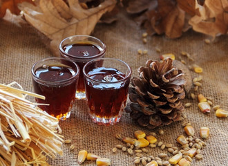 Christmas concept, Three glasses full of honey syrup on rustic canvas.beside big pine cone, wheat seeds, and maize seed