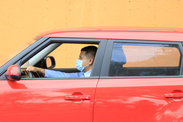 Naklejka premium Hombre con cubrebocas manejando auto