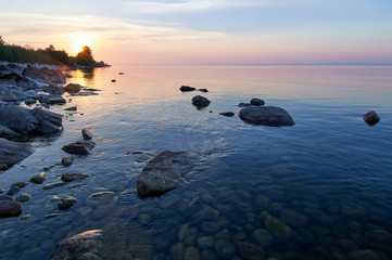 Fototapeta na wymiar Lake Baikal in the summer at dawn. In the foreground is clear water and stones under water.