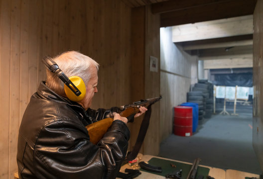 Senior man aiming with a gun in shooting range