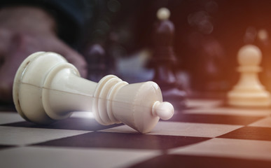Surrender of king on chess board. White king down signifying a loss, close up. Business challenge,...