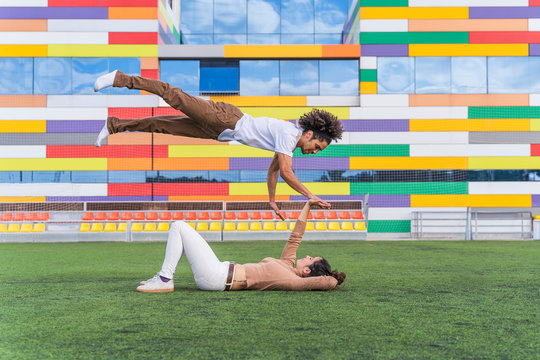 Dancer jumping mid air over partner, lying on grass