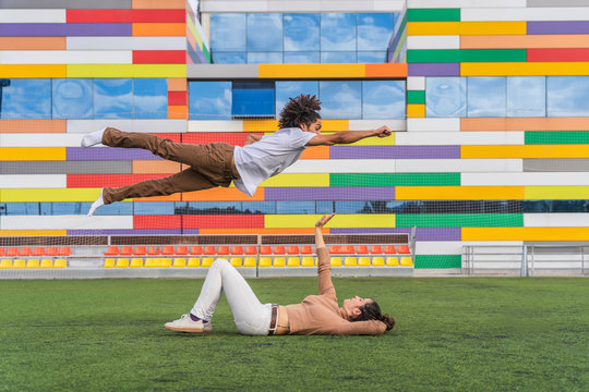Dancer jumping super hero style over partner, lying on grass