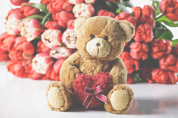 A large tulip bouquet, many flowers with red blossoms. With teddy bear.