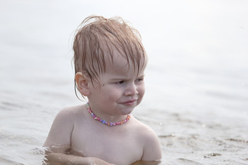 little independent girl sitting in the water on the lake