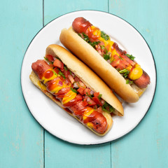 Hot dog with pico de gallo salad on turquoise background