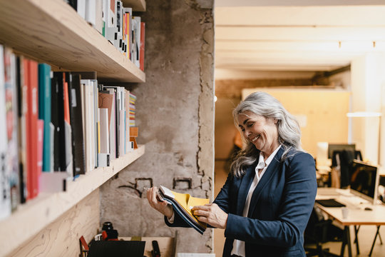 Smiling grey-haired businesswoman holding color samples in a loft office
