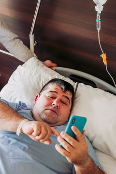 Patient lying in hospital bed using cell phone