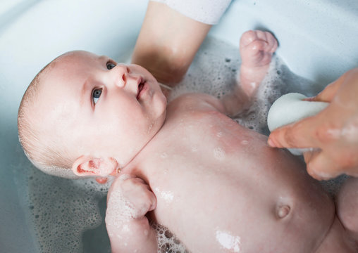 Mother bathing her baby boy in a tub