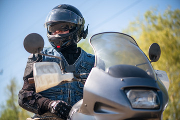 Biker in a helmet on the motorbike is looking aside close up.