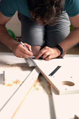 Man doing renovation work at home, drilling with a screwdriver. Group of repair tools on wooden white background.