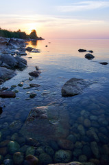 Naklejka premium Lake Baikal in the summer at dawn. In the foreground is clear water and stones under water.