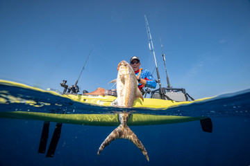 Split shot of happy man in a kayak catching a fish