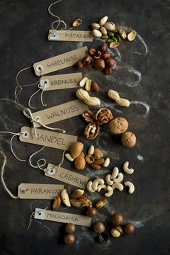 Collection of various nuts with name tags lying on rustic baking sheet