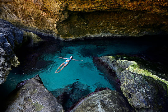 Woman floating on clear watr in a grotto