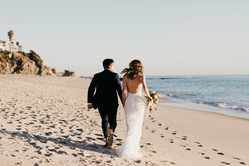 Rear view of happy bridal couple running at the beach
