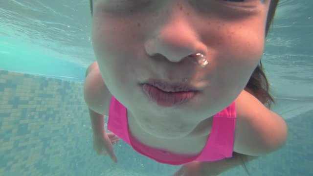 funny little girl swims in the pool underwater and holds her breath. Learning to swim children, concept