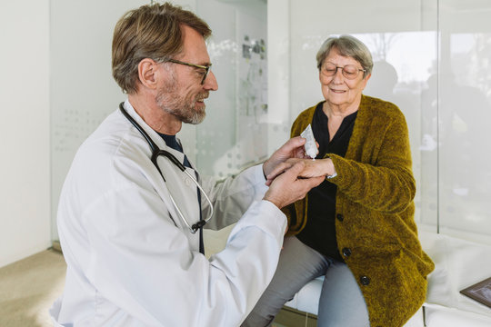 Doctor putting ointment on hand of senior patient
