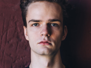 closeup portrait of a serious young man, teenager on wall background