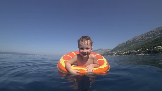 Little cute cheerful boy swims in an inflatable ring in the sea. Croatia, Adriatic Sea, Europe