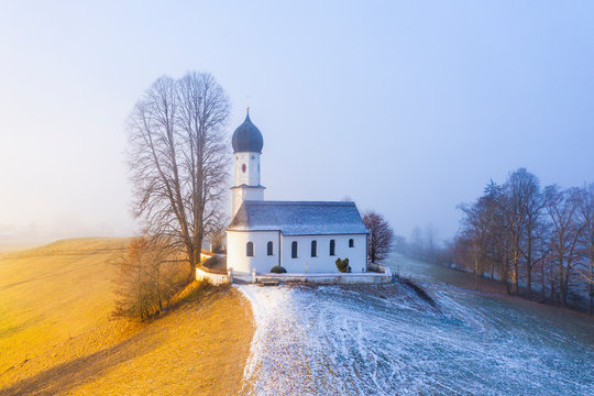 Germany, Bavaria, Bad Heilbrunn, Drone view of Kirche Maria Heimsuchung at foggy winter dawn