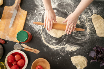 Woman's hands rolling out dough on worktop