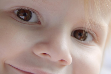Close up of the face of a smiling little girl with blond hair in a car