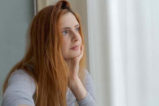Portrait of serious young woman looking out of window