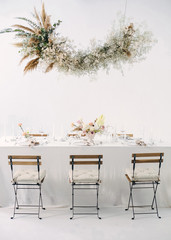 Obraz premium festive table with a floral bouquet, candles, chairs and a flower garland