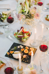 holiday table with  black square plate with  cheese, pine nut and figs