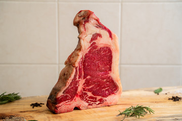 una bistecca cruda su un tagliere di legno con rosmarino