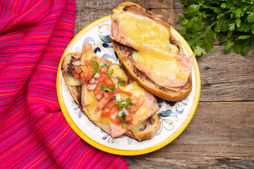 Mexican molletes with ham and cheese on wooden background