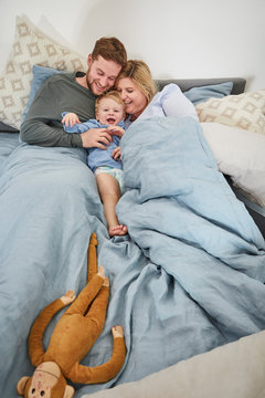 Family cuddling togehter on bed