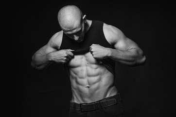 Sporty guy posing in the Studio on the background. Sports, beauty, black and white photography