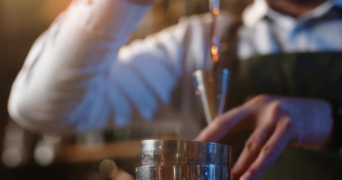 Professional bartender masterly creating a cocktail in modern bar. Experienced barman adding syrip into shaker using jigger - food and drink, nightlife close up 4k footage