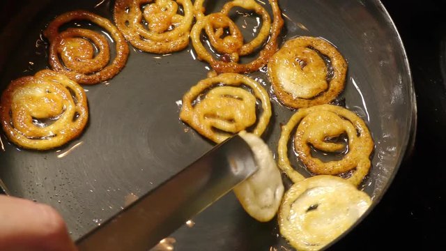 Making and frying jalebi with white liquid maida atta in pan with heated oil