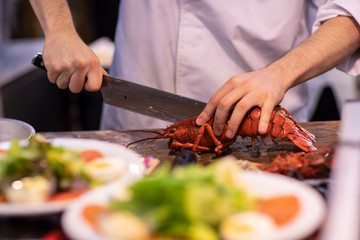 A cook in a white suit cutting a lobster and preapring fresh healthy dishes in a kitchen envionment