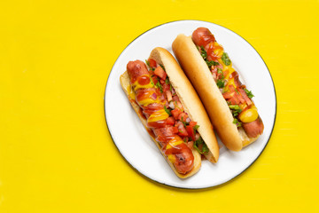 Hot dog with pico de gallo salad on yellow background