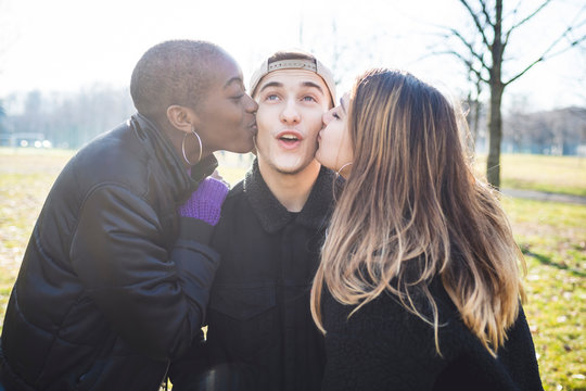 Two girls kissing their friend on his cheaks