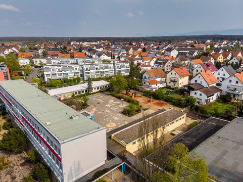 Beautiful Top View Of The School And School Yard. Children's Drawings On The Pavement. Orange, Tiled Roofs Of Houses. No Students. Pandemic. Covid-19. Viernheim, Germany.