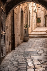 A small alley with old limestone pavements in the old town in Dubrovnik, Dalamtia, Croatia on a sunny day in summer. Ancient street with stairs in the medieval historic town in Europe in summer