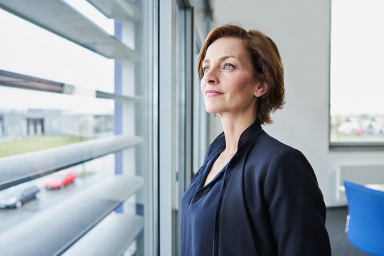 Portrait of confident businesswoman looking out of window - Powered by Adobe